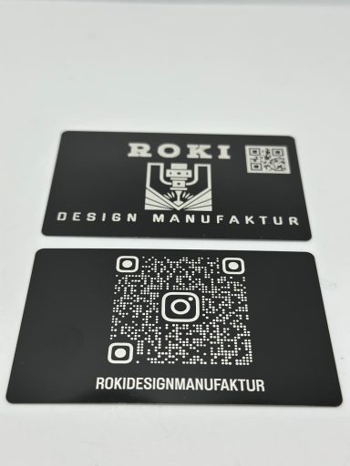 Schwarze Visitenkarten mit QR-Code und dem Text "ROKI DESIGN MANUFAKTUR".